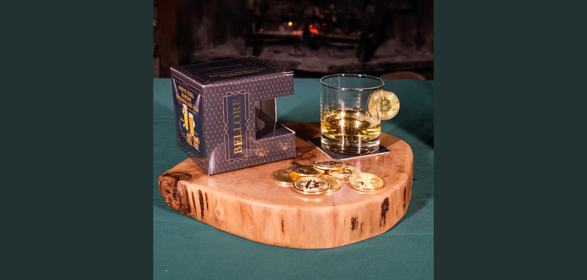 Bellore whisky glass with a Bitcoin-emblem coin set into the glass, on a wooden surface